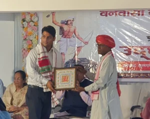 Felicitation at the building’s opening ceremony in Ranchi: man receiving a shawl and framed memento on stage