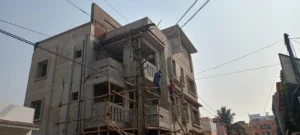 Exterior plastering stage of a three-storey house in Bokaro with bamboo scaffolding and workers on site