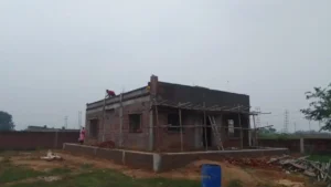 Brickwork stage of a single-storey farmhouse near Ranchi with bamboo scaffolding and workers on the roof sla