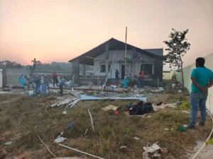 Workers plastering the walls and fixing the roof frame of a farmhouse near Ranchi at sunset