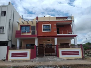 G+1 house construction in Ranchi: home with red-orange and yellow walls, maroon bands and brown slatted gate