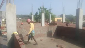 RCC columns and brick walls rising on a house construction site in Ranchi with a mason at work