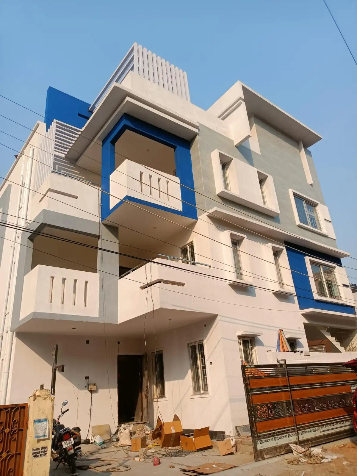 1750 sq ft house construction in Bokaro: white home with grey and blue highlights, tile cladding and MS pergola
