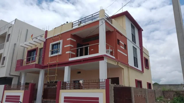 Side view of a G+1 house in Ranchi with steel and glass balcony railing, white pillars and rooftop railing