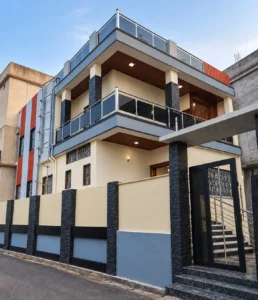 Vastu house construction in Ranchi: duplex home with cream walls, black stone-look columns and glass balcony railing